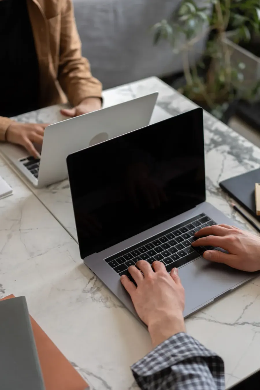 Two people working on laptops at a marble table