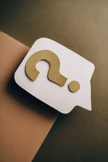 A white speech bubble with a golden question mark on brown paper