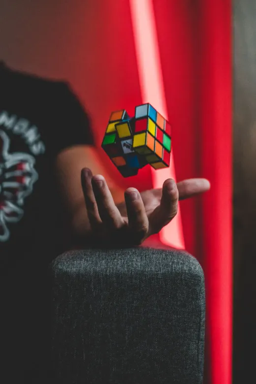 A multicoloured puzzle cube floating above an open hand
